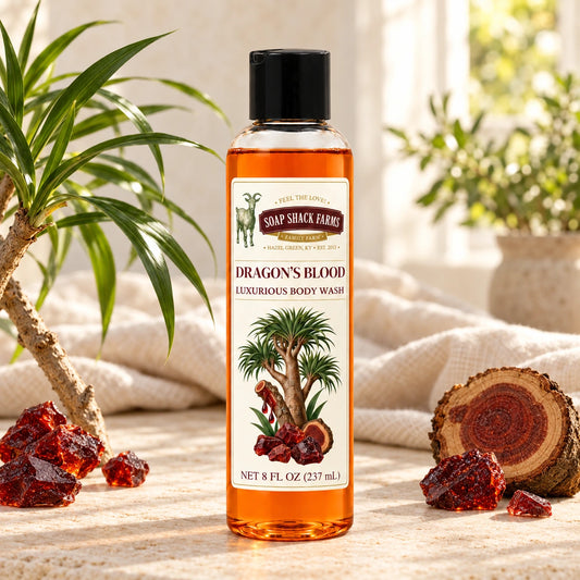Dragons Blood luxurious body wash with botanical foliage, deep-red resin pieces, wood, and farmhouse linen.