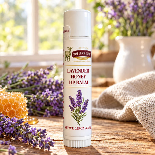 Soap Shack Farms Lavender Honey Lip Balm in a white 0.15 oz tube on a rustic wooden table with linen in a sunlit farmhouse setting.