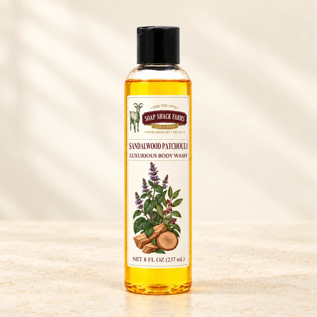 Sandalwood Patchouli luxurious body wash in a slender clear bottle on a warm cream studio background.
