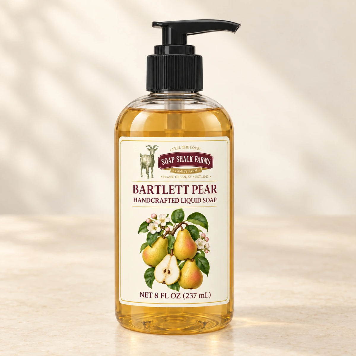 Bartlett Pear handcrafted liquid soap in a clear pump bottle on a warm cream studio background.