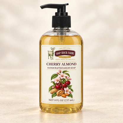 Cherry Almond handcrafted liquid soap in a clear pump bottle on a warm cream studio background.
