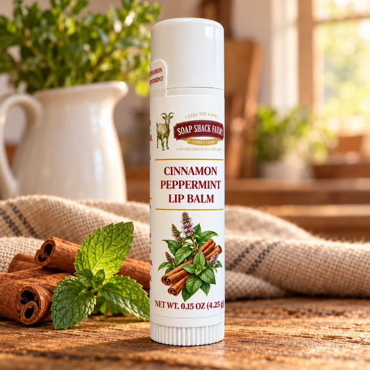 Soap Shack Farms Cinnamon Peppermint lip balm on a rustic wooden table with cinnamon sticks, peppermint, linen, and a softly lit farmhouse kitchen.