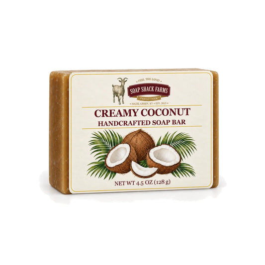Creamy Coconut handcrafted olive oil soap bar with coconut and palm botanical label on a white background.
