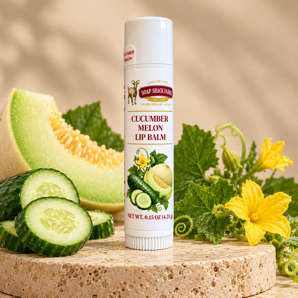Soap Shack Farms Cucumber Melon Lip Balm in a white 0.15 oz tube on a stone surface with flavor-inspired botanicals in a warm studio setting.