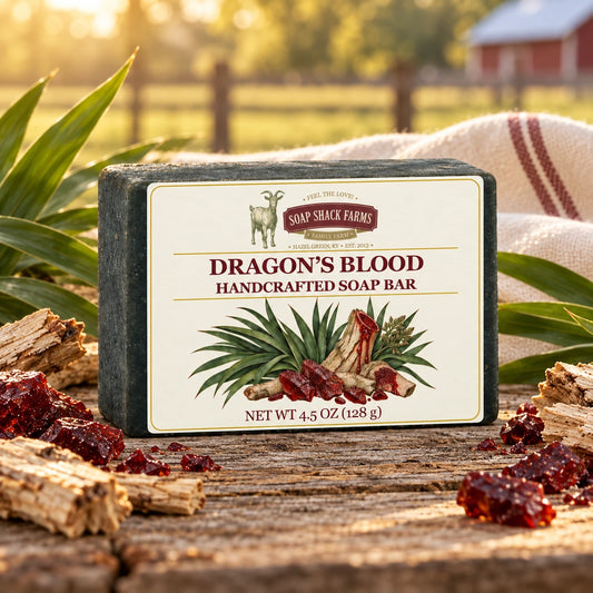 Dragon’s Blood olive oil soap bar on rustic wood with dracaena leaves, bark, and burgundy resin.