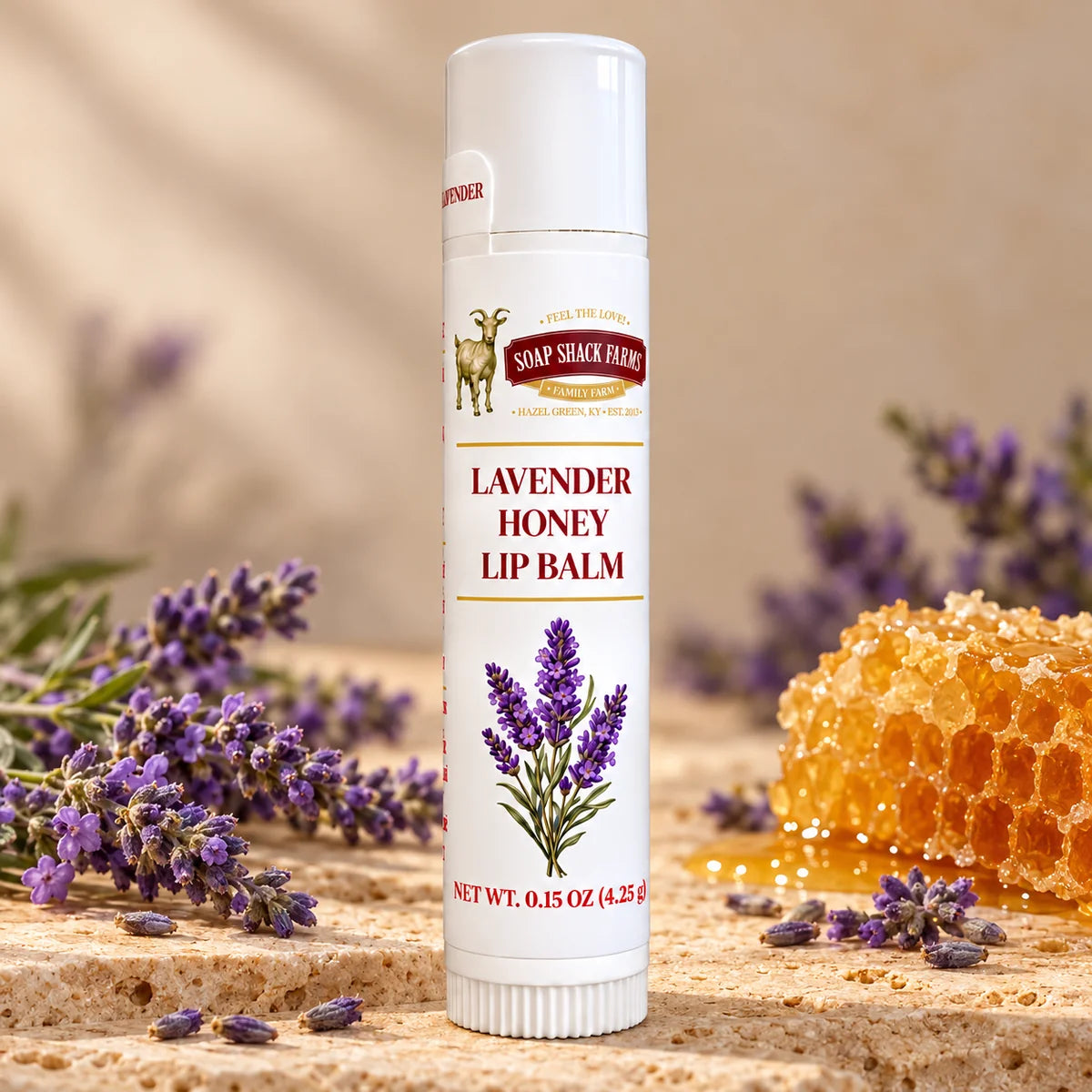 Soap Shack Farms Lavender Honey Lip Balm in a white 0.15 oz tube on a stone surface with flavor-inspired botanicals in a warm studio setting.