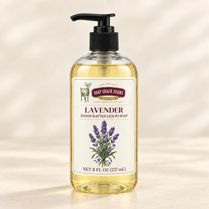 Lavender handcrafted liquid soap in a clear pump bottle on a warm cream studio background.