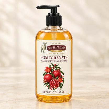 Pomegranate handcrafted liquid soap in a clear pump bottle on a warm cream studio background.