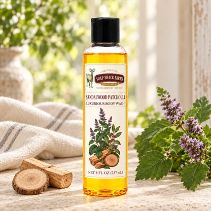 Sandalwood Patchouli luxurious body wash with sandalwood pieces, patchouli leaves, purple flower spikes, and farmhouse linen.