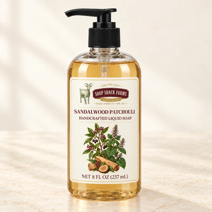 Sandalwood Patchouli handcrafted liquid soap in a clear pump bottle on a warm cream studio background.