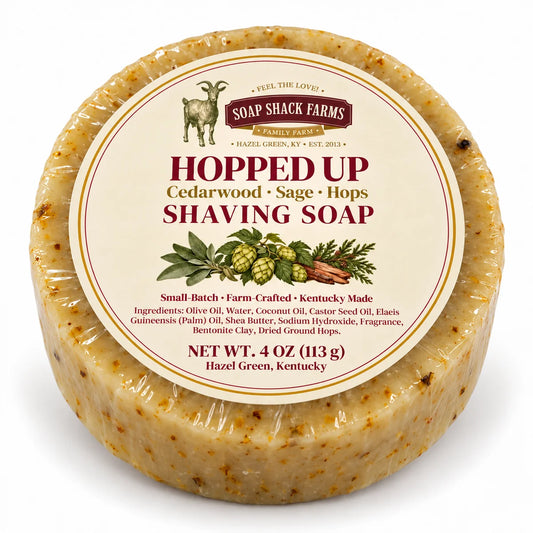 Round speckled Hopped Up shaving soap by Soap Shack Farms, wrapped with a cream botanical label on a white background.