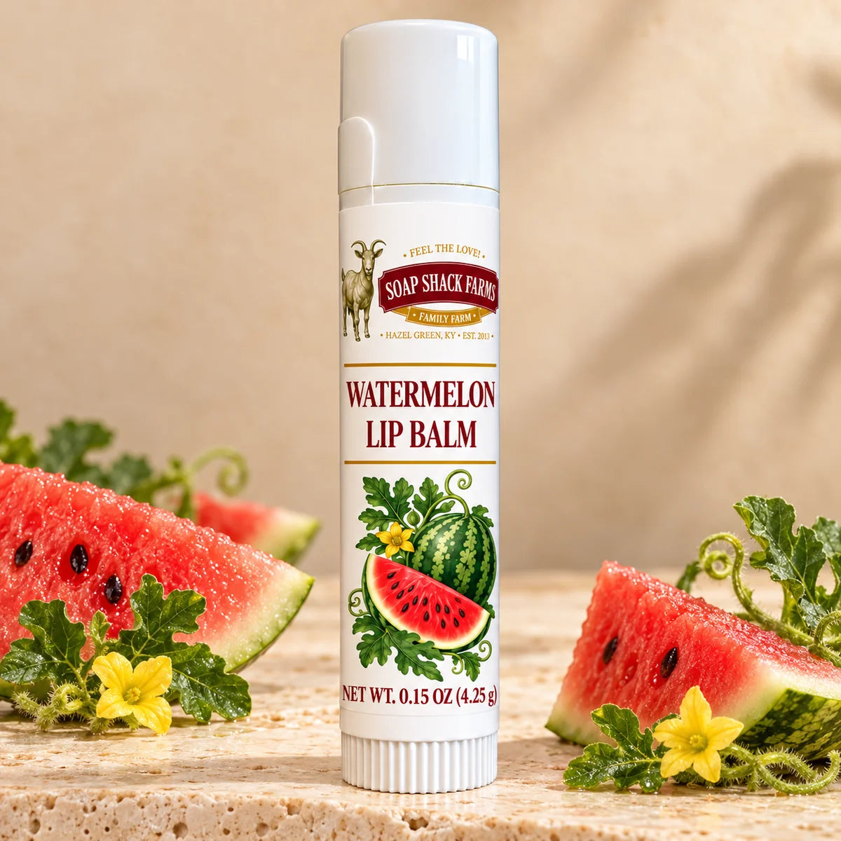 Soap Shack Farms Watermelon Lip Balm in a white 0.15 oz tube on a stone surface with flavor-inspired botanicals in a warm studio setting.