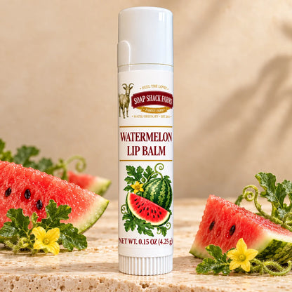Soap Shack Farms Watermelon Lip Balm in a white 0.15 oz tube on a stone surface with flavor-inspired botanicals in a warm studio setting.